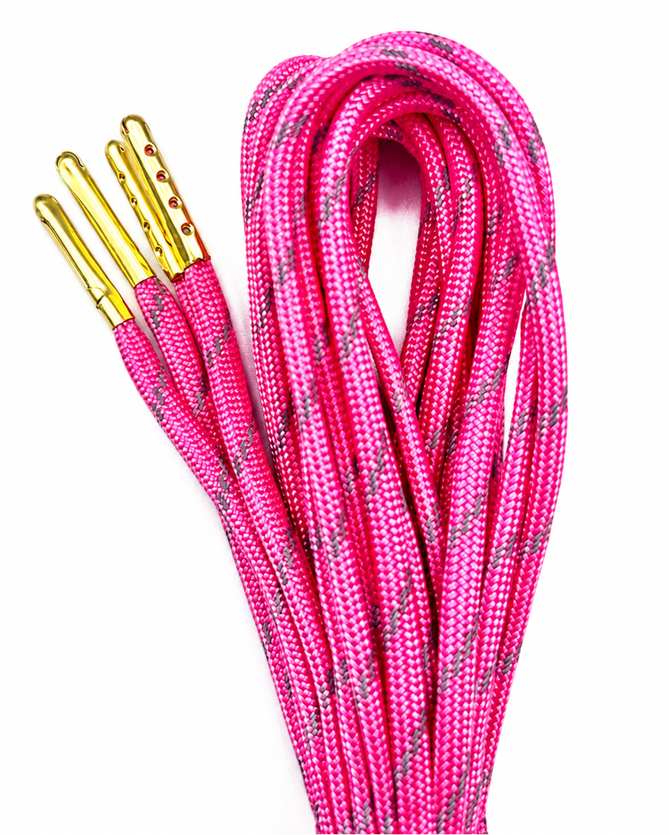 Light pink paracord skate laces with gold metal tips, coiled on a white background.