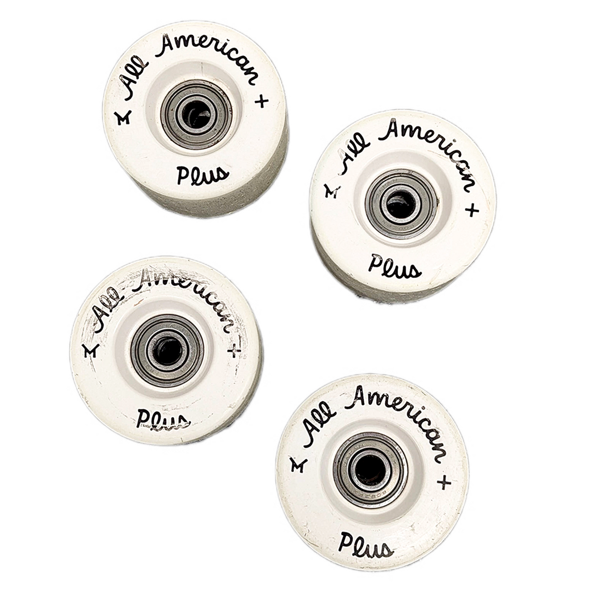 Four OG All American Plus Roller skate wheels arranged on a plain white background, each showing the inner bearing and printed branding.